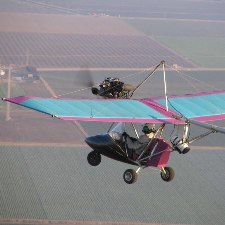 Russell flying his ultralight over farm fields, camera mounted on the wing strut
